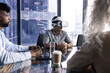© Wavebreak Media - At office, diverse team at table, Asian man wearing VR headset