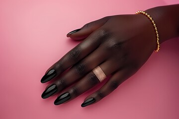 Wall Mural - Female hand with black manicure and jewelry on a pink background.