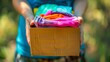 volunteer hands holding clothes donation box filled with colorful clothing items charity concept photo