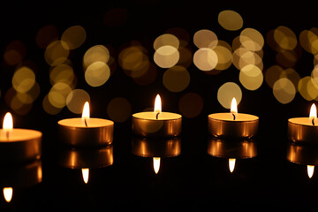 Wall Mural - Burning candles on mirror surface in darkness, bokeh effect