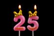 Burning pink birthday candles with gold bow and word happy isolated on black background, number 25.
