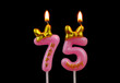 Burning pink birthday candles with gold bow and word happy isolated on black background, number 75.