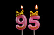 Burning pink birthday candles with gold bow and word happy isolated on black background, number 95.
