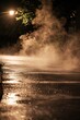 Steam rising from hot pavement after a summer rain shower, creating a hazy, atmospheric effect, Generative AI