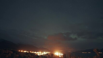 Wall Mural - Northern lights in the night sky above the brightly illuminated ort and the fjord.