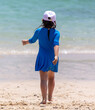 A girl walks along the white sand by the sea. Back view