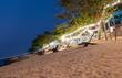 Sun loungers on the sandy beach in the light of lanterns at night