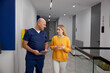 Nervous woman talking to doctor while walking through hospital corridor
