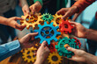 © ink drop - Close up of a team of business people holding colorful gears in their hands working together