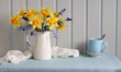 spring flowers in a white jug. yellow daffodils and blue hyacinths. still life, cottage interior.