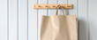 Brown paper bag hanging on a wooden hanger, close-up. Natural background, copy space. Concept: no plastic.