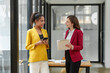 © crizzystudio - Two businesswomen working together using documents Work files talk about business projects. Creative team of African American female executives stand meeting in modern office.
