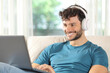 Happy man watching media on laptop sitting at home