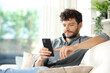Serious man using phone on a couch at home