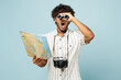 © ViDi Studio - Traveler amazed Indian man in white casual clothes hold read map use binocular isolated on plain blue background Tourist travel abroad in free spare time rest getaway Air flight trip journey concept