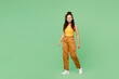 © ViDi Studio - Full body side view young woman of African American ethnicity wear yellow tank shirt top walking going look camera isolated on plain pastel light green background studio portrait. Lifestyle concept.