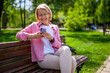 Portrait of happy mature woman in park. She is messaging on phone.