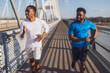 Two african-american friends are jogging on the bridge in the city.