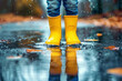 © Annamorphosis - A person in yellow rain boots is standing in a puddle of water