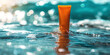 Vibrant orange sunscreen tube afloat amidst sparkling ocean water under bright daylight