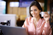 © PheelingsMedia - Happy elegant woman holding coffee and using laptop looks at you