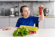Cute little pre-teen girl looking at a sprig of tomatoes sitting in the kitchen at home in front of a plate of vegetables and salad. Selected focus