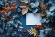 Dark blue background with white card in the center surrounded by autumn leaves and berries. A beautiful flat lay composition for an elegant greeting or invitation design nature concept.