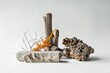 A minimalist scene with various natural stone textures, such as different marble, twigs, and moss. The composition is in shades of gray-brown with orange accents against a white background.