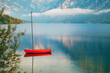 Red boat floating on tranquil lake Bohinj surface in summer morning