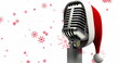 Image of microphone with santa claus hat over snowflakes on white background