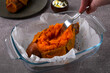 Cooking baked stuffed sweet potato. Scraping and stirring the baked pulp with the fork to add the next ingredient