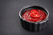Gochujang Korean traditional spicy fermented sauce in a bowl and chili pepper on a dark background.