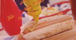 Image of hot dog icons over hot dogs being prepared