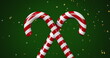 Image of stars over candy canes on green backrgound