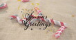 Image of seasons greetings text and stars over candy canes on beige backrgound