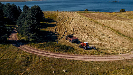 Aerial view of a red tractor plowing golden fields, depicting the concept of agriculture and related to the harvest season or Earth Day