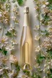 An artistically designed champagne bottle nestled among spring white flowers, showcasing elegance and celebration.


