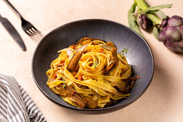 Poster - Close up of a plate with artichokes pasta, fettucine and bacon,  seasoned with saffron and thyme. Italian food. Fresh flower of artichoke on background.