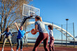 Group of young woman having fun playing recreational basketball outdoors.