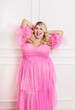 Joyful plus size model in pink dress