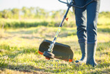 Fototapeta  - worker mows green grass on the lawn with hand trimmer. lawn care. weed control. Woman with gasoline mower cutting grass. Grass trimmer worker, garden work.