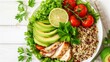 Top-down view of a grilled chicken breast with avocado, quinoa, cherry tomatoes, and greens on a white surface