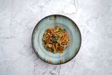 Wall Mural - Udon noodles with baked vegetables on a marble table background