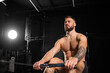 Man exercising on rowing machine, wearing only shorts, bare chest. Routine workout for physical and mental health.
