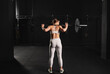 Rear view of woman pressing barbell up, standing up. Routine workout for physical and mental health.