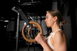 Beautiful sport woman standing by rings in gym, preparing for exercising. Routine daily workout for female health.