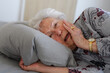 Senior woman lying in her bed alone. Woman having pain a feeling anxious. Loneliness and social isolation of eldery woman.