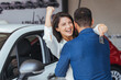 Happy couple embracing after receiving keys from their new car in a showroom. Yay honey, we have bought a new car! Happy couple buying a car at the dealership and holding the keys