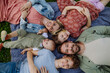 Top view of family lying on grass, portrait with two parents, son, daughter and small toddler outdoors in spring nature