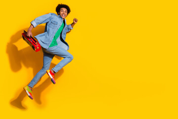 Poster - Full size portrait of nice young man boombox run jump empty space wear denim shirt isolated on yellow color background